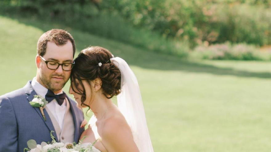 Bride and groom smiling on a sunny, grassy field.