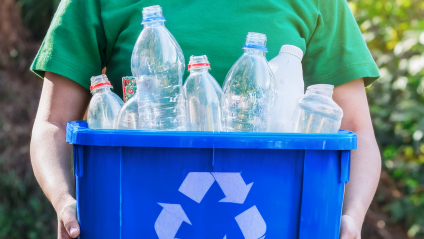 Woman holding a blue recycle bin with recycled bottles inside the bin