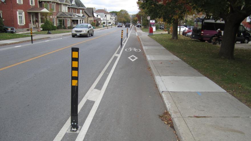 Bike lane on a suburban street lined with houses and trees.