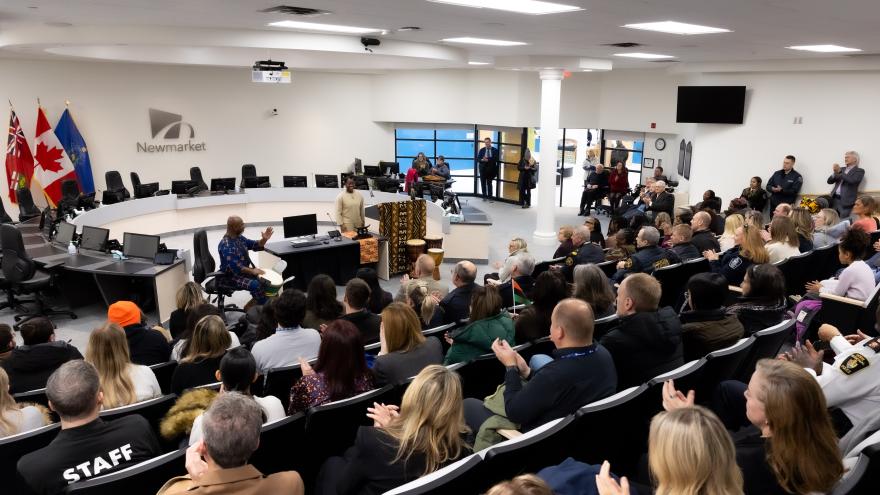 Crown of people in a room with a speaker at a podium