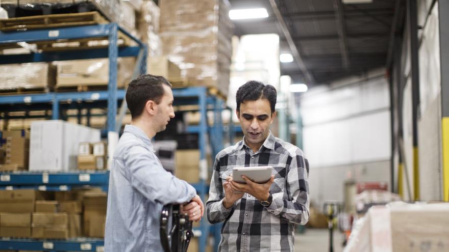 two people chatting about business in a warehouse stock room