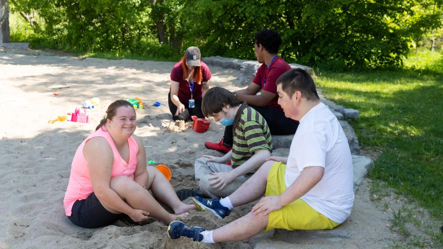 People sitting in the sand at a playground
