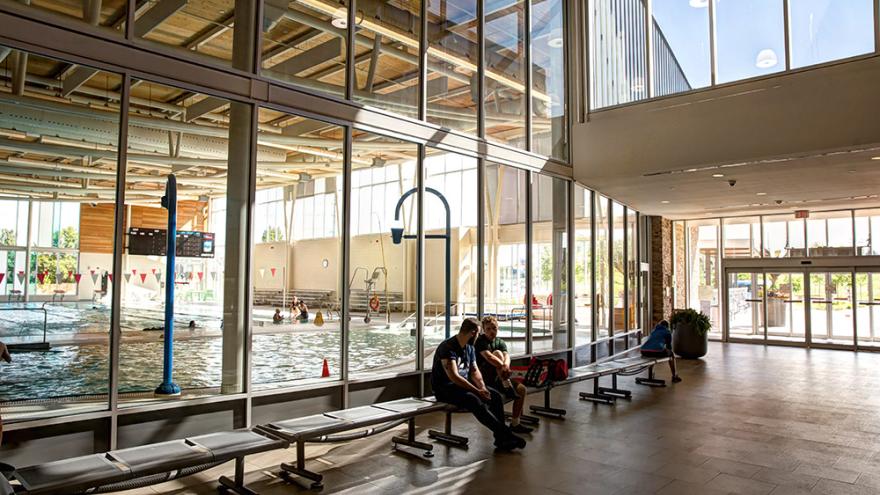 People sitting on bench outside an indoor pool enclosure