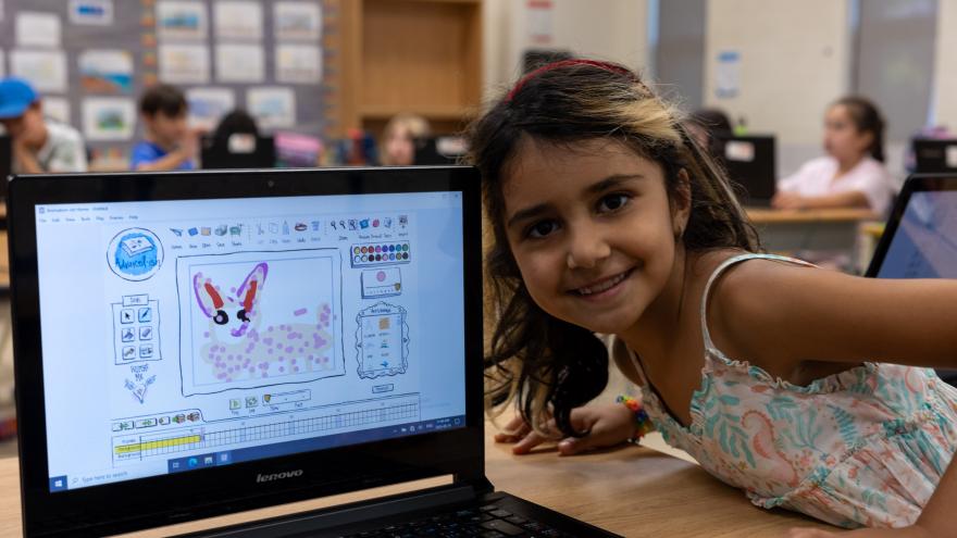 Child posing in front of a laptop