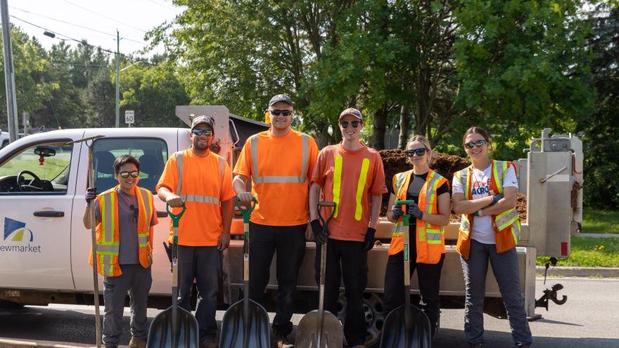 Group of people holding shovels standing in front of a truck