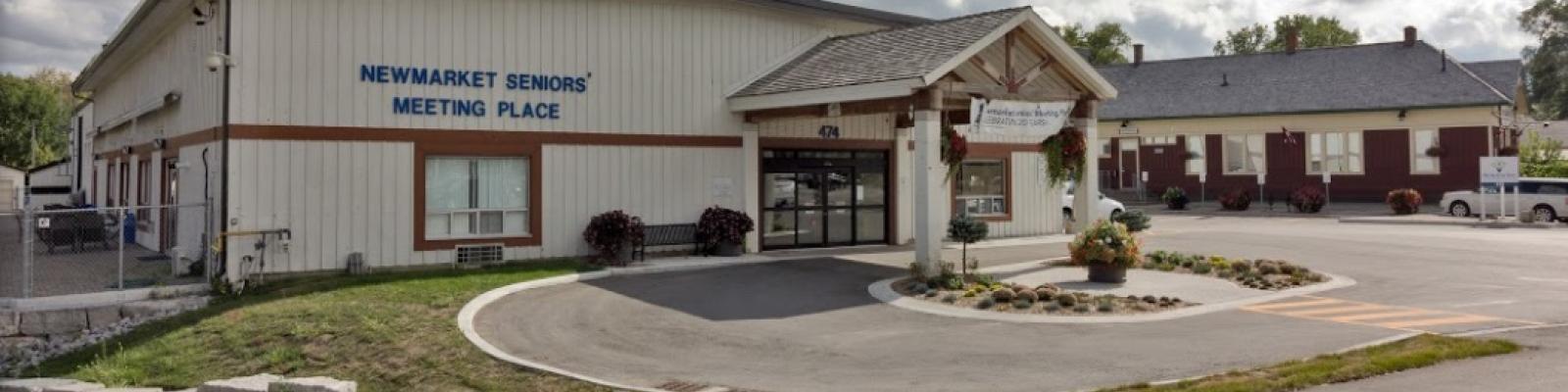 Community center with a parking lot, cloudy sky.