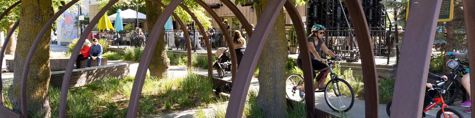 Outdoor space with trees and greenery with people biking on walkway