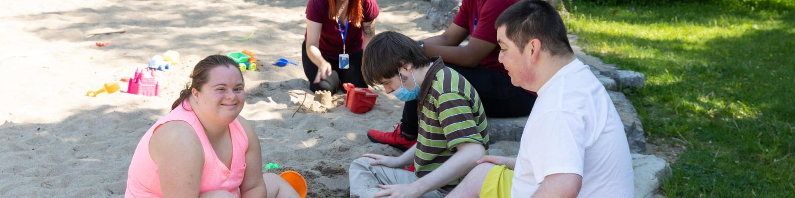 People sitting in the sand at a playground