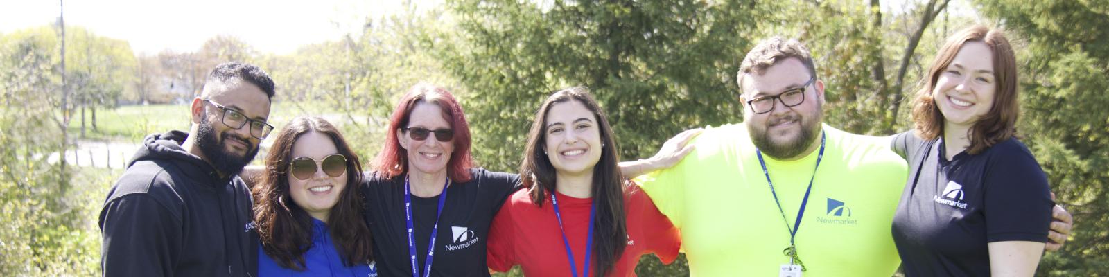 People standing arm in arm on a grassy area outdoors