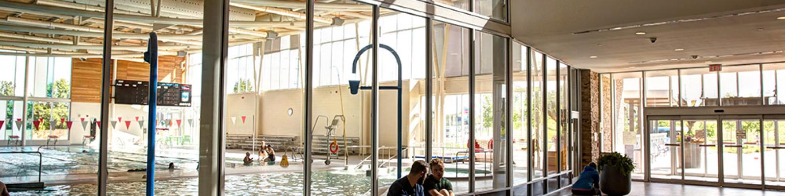 People sitting on bench outside an indoor pool enclosure