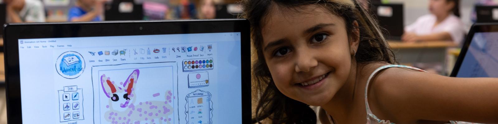 Child posing in front of a laptop