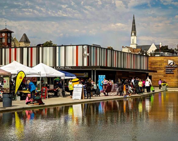 Newmarket Riverwalk Commons, Building with water feature and booths outside.