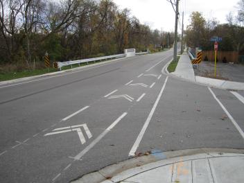 Curved road with bike lane markings and autumn trees.