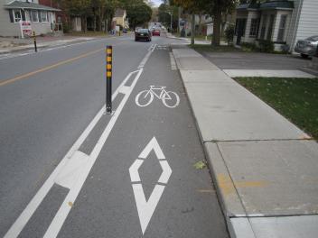 Bicycle lane with symbols, adjacent to a road and sidewalk.