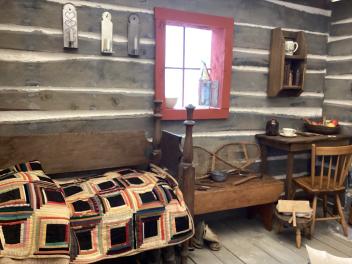 Cozy log cabin room with quilted bed, wooden table, and window.