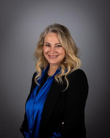 Grace Simon smiling wearing a blue blouse and black blazer.