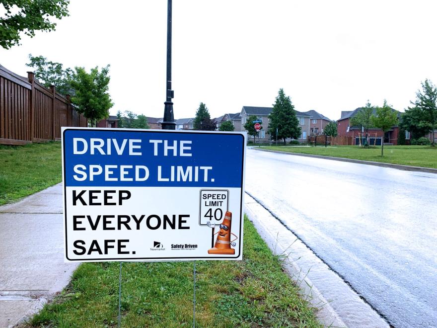 Speed limit sign beside a wet suburban road.