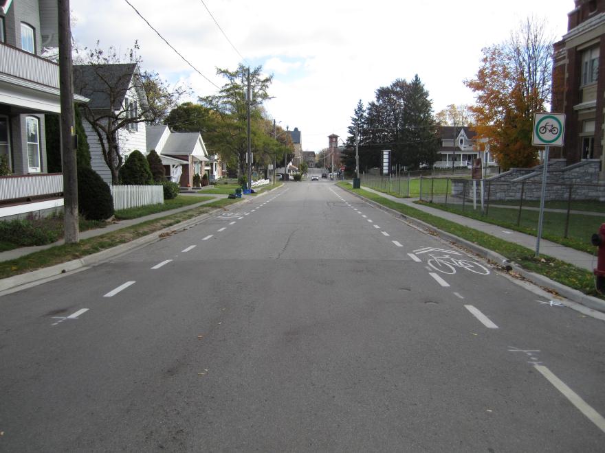 Quiet suburban street with bike lane and fall trees.