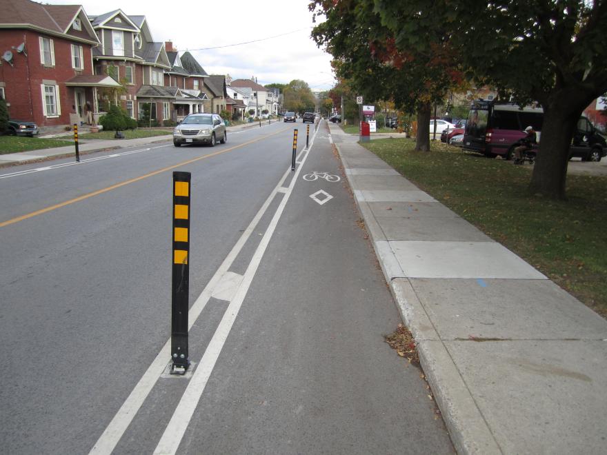 Bike lane on a suburban street lined with houses and trees.