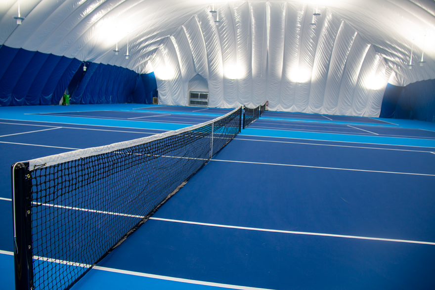 Indoor tennis court with blue flooring and a net.