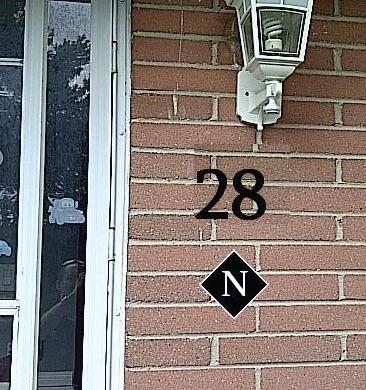 Brick wall with house number 28, and a diamond plate with an N.