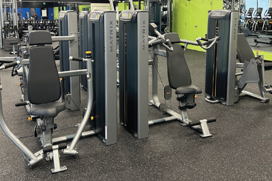 Gym with various weight machines on a black floor.