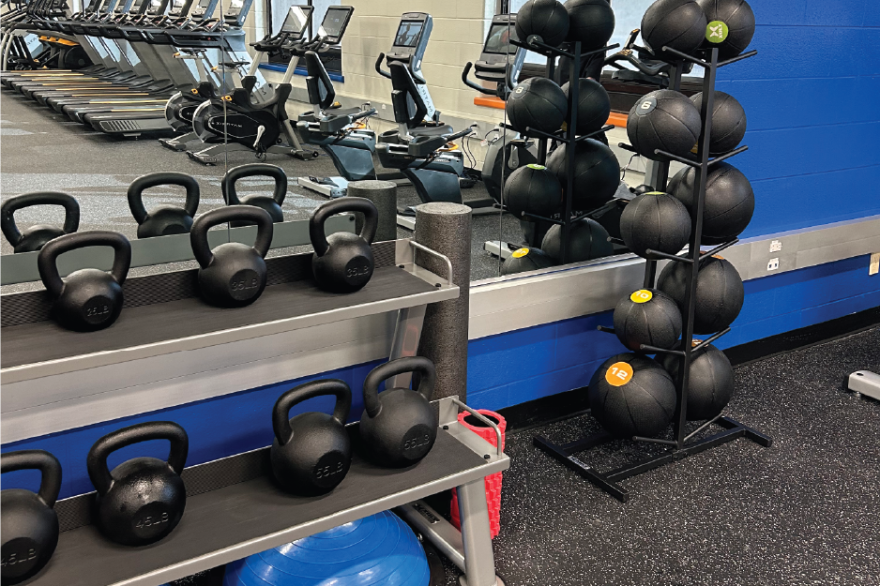 Kettlebells and medicine balls in a gym with exercise equipment.