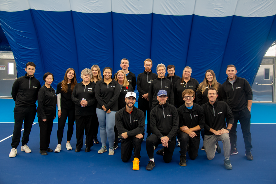 Group of people in matching outfits on an indoor tennis court.