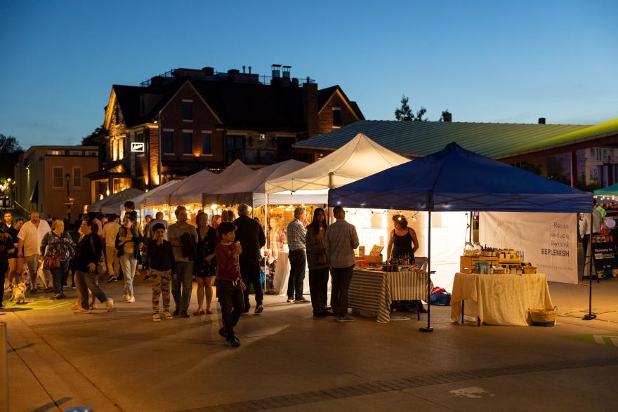 Night market with people browsing lit-up vendor tents.