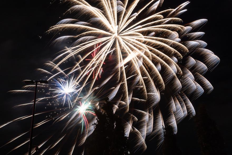 Fireworks with white and red bursts in a dark sky.