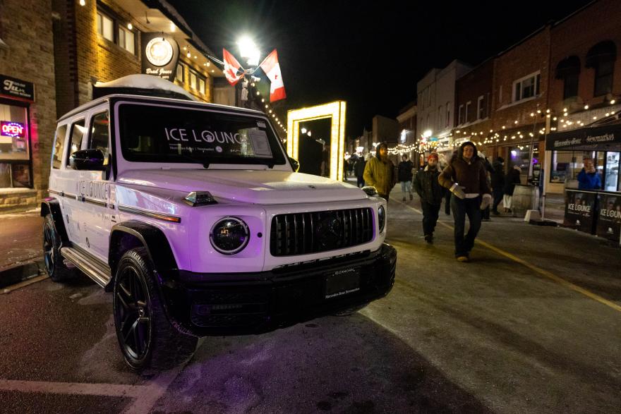 Vehicle with the words "Ice Lounge" written on it on a street with a crowd nearby
