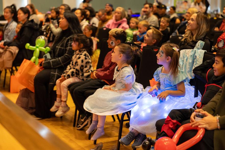 Parents and kids in costumes sitting in a crowd