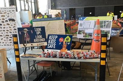 Safety exhibition table with signs, maps, and toy traffic cones.