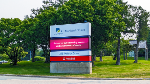 Municipal office sign with trees and grass behind.