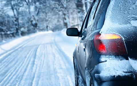 Car on snowy road with rear lights glowing.