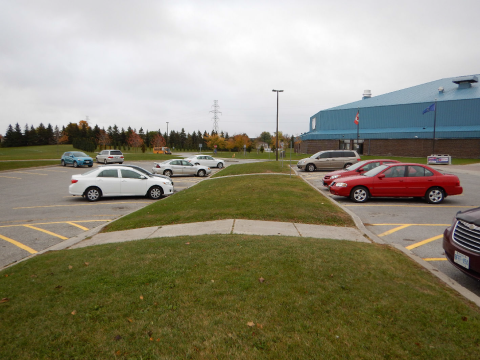 Parking lot with cars, grassy median, and cloudy sky.