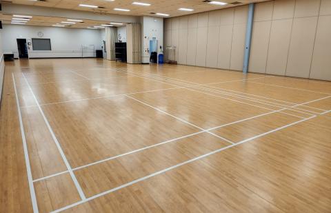 Spacious gymnasium with a wooden floor and white court lines.