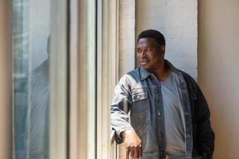 Man in denim jacket gazing out a window.