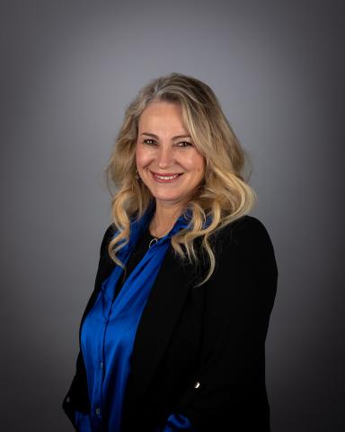 Grace Simon smiling wearing a blue blouse and black blazer.