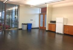 Empty room with a fridge, trash cans, and cabinets.