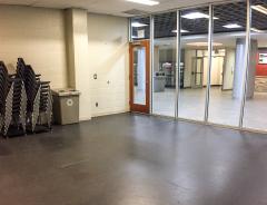 Empty room with stacked chairs, glass doors, and a recycling bin.