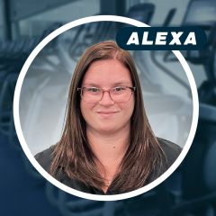 Smiling woman with glasses in a gym setting.