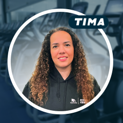 Woman with curly hair in a gym setting, wearing a black hoodie.
