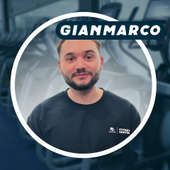 Young man with beard in a gym, wearing a black shirt.