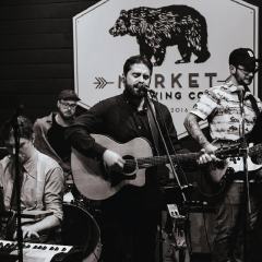 Band performing on stage, guitarist singing, black and white photo.