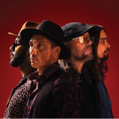 Four people in hats and patterned shirts against a red background, looking serious.