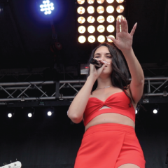 Singer in red outfit performing on stage.