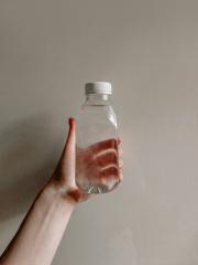 Person holding up a glass bottle of water