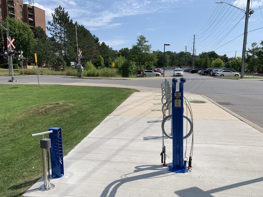 Sidewalk with a public bike repair station under a clear sky.