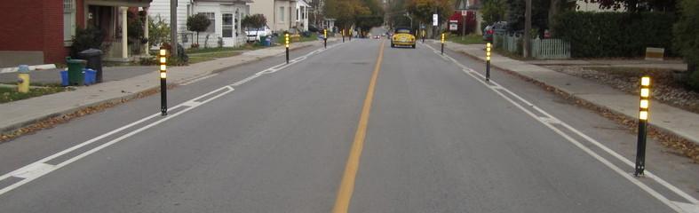 Wide street with yellow center line and bollards on sides.